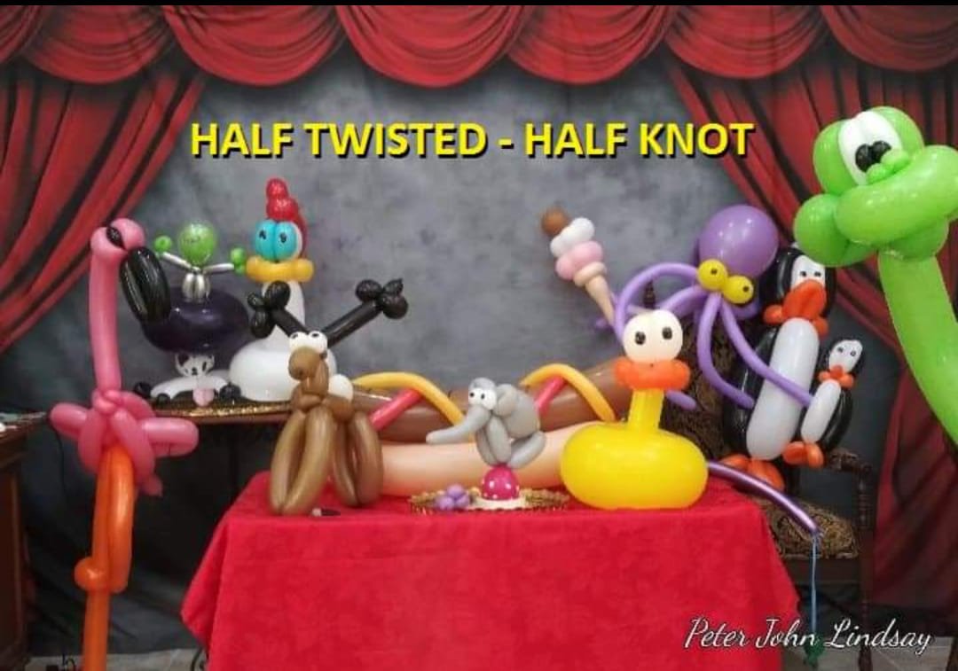Colorful balloon animals displayed onstage beneath the words “Half Twisted – Half Knot”