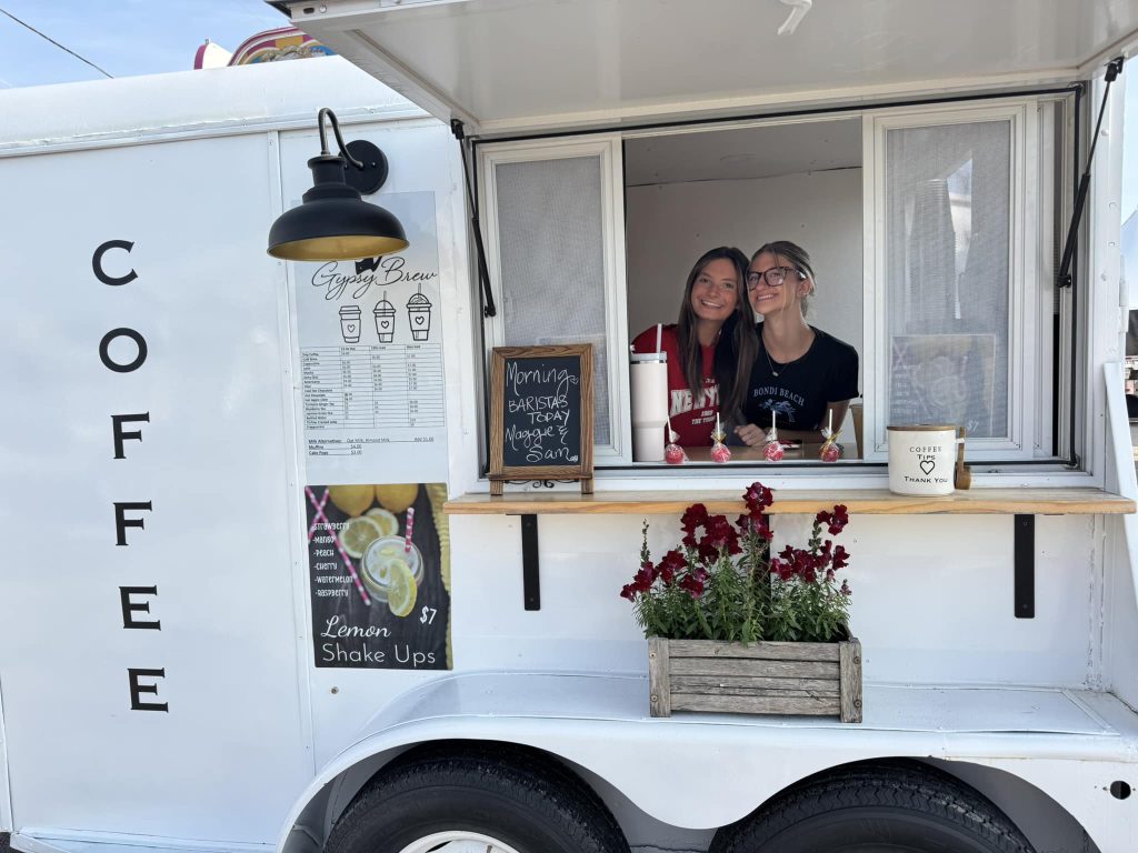 Two smiling baristas at the service window of the Gypsy Brew coffee trailer